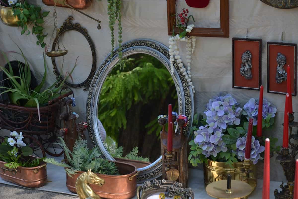 Artistic arrangement of vintage home decor items including a mirror, candles, and dried flowers in a moody setting, evoking the eerie histories of allegedly haunted and cursed mirrors