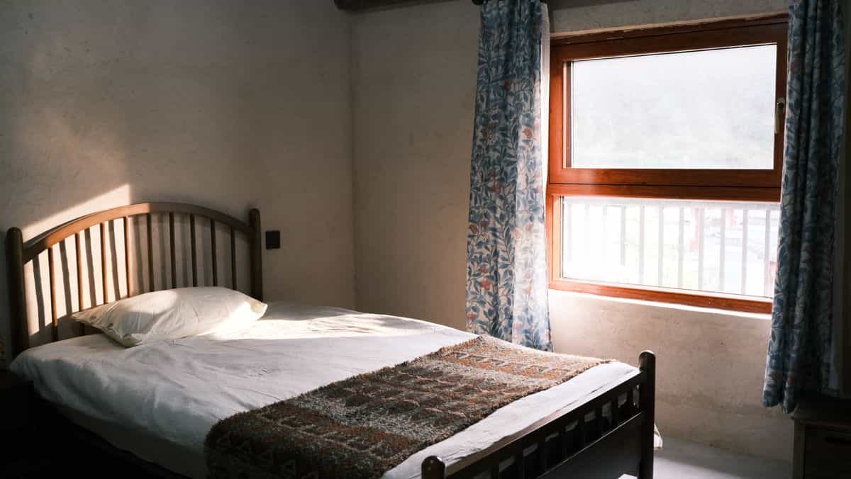 Bed near a window illustrating feng shui bed positions to avoid Bedroom with a bed beside a sunlit window, illustrating feng shui bed positions to avoid such as under a window