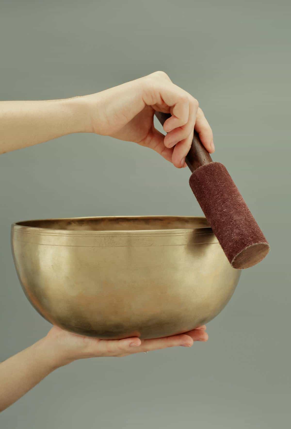 Brass singing bowl and wooden mallet on neutral fabric in calm meditation setting