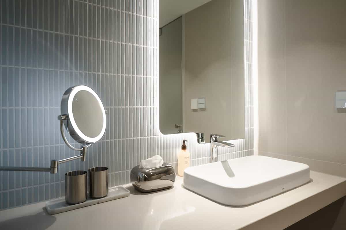 Minimalist white bathroom vanity with round mirror and warm side lighting