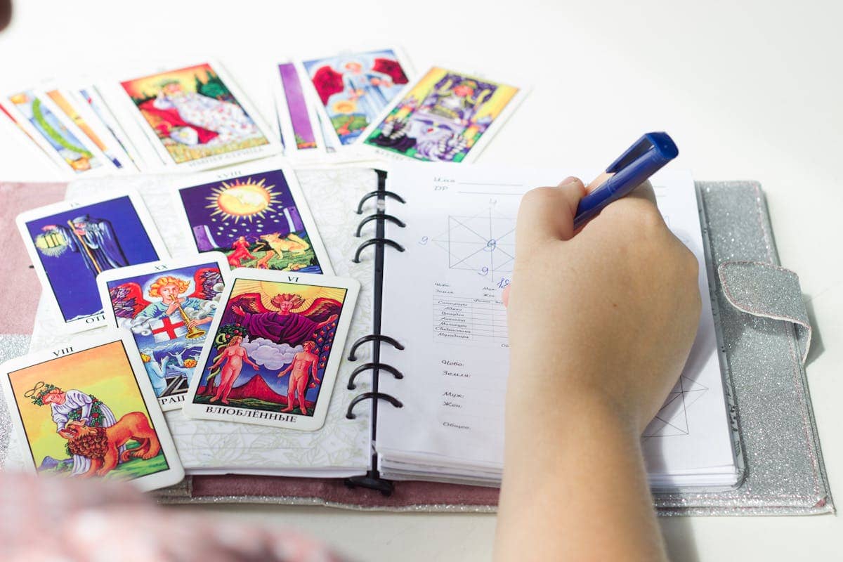 Spiritual journal and tarot cards arranged on a desk representing the reflective practice of recording scrying insights