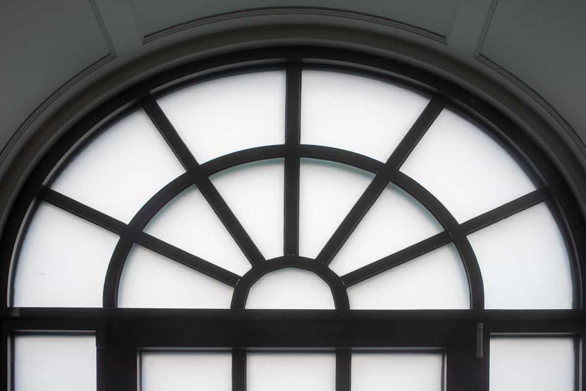 Black-framed arched window illustrating the window-pane arched mirror look Elegant arched window with a classic black frame and frosted glass, illustrating a window-pane arched mirror