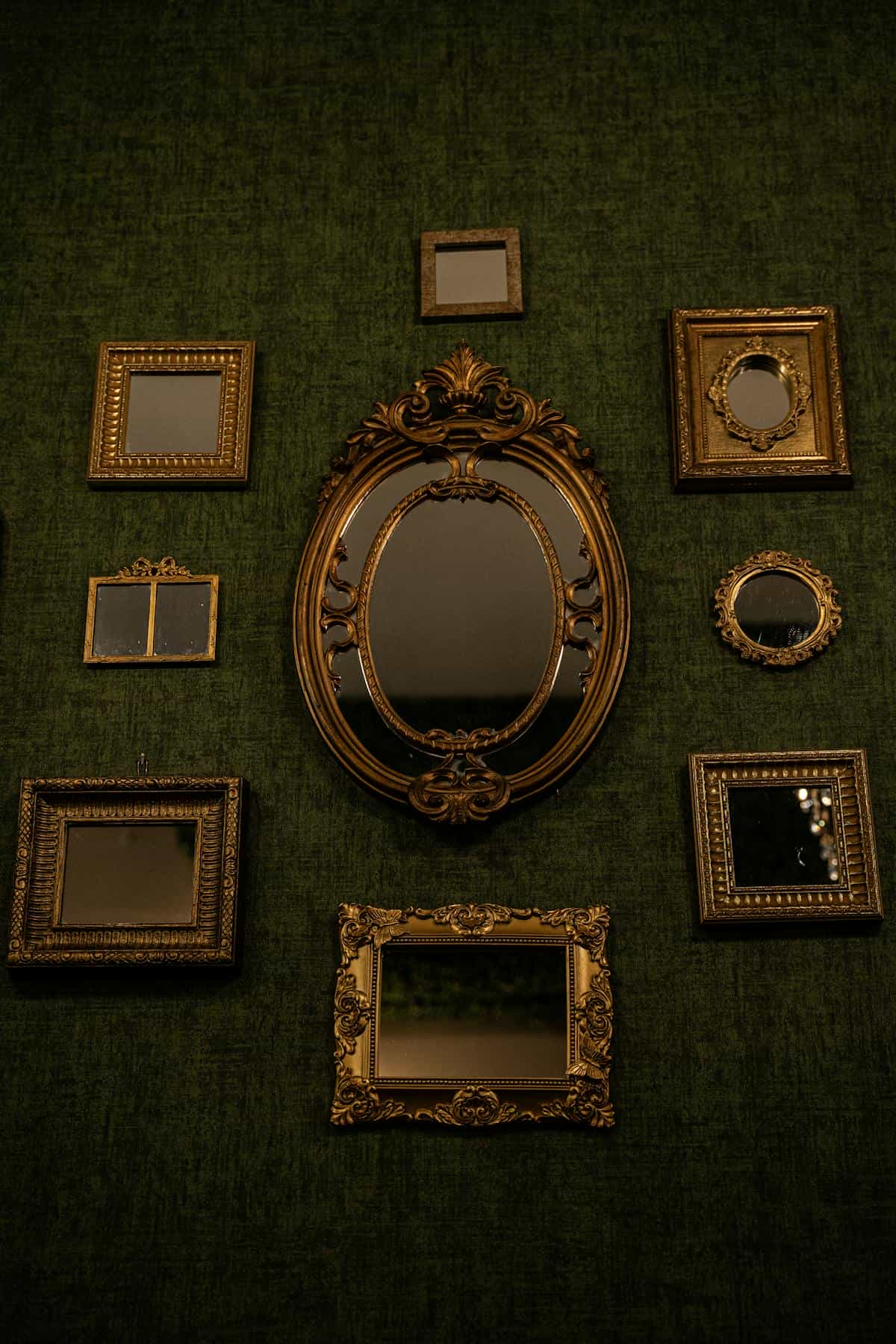 Vintage ornate mirrors on wall illustrating cultural mirror symbolism and reflection Collection of vintage ornate mirrors on textured green wall showing historical mirror craft and spiritual symbolism