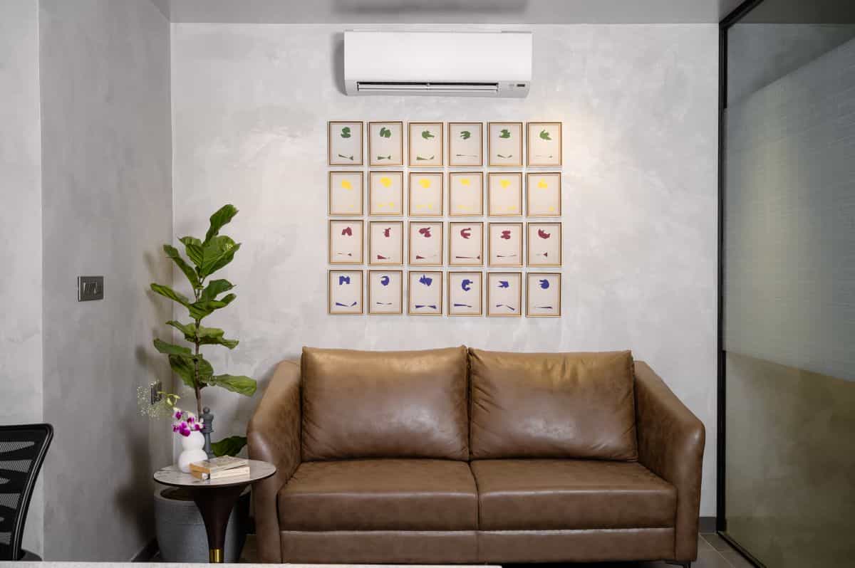 Living room wall art above a sofa illustrating how to size magnolia wall art to furniture Living room with a brown sofa, wall art and a potted plant, illustrating how to size magnolia wall art above furniture
