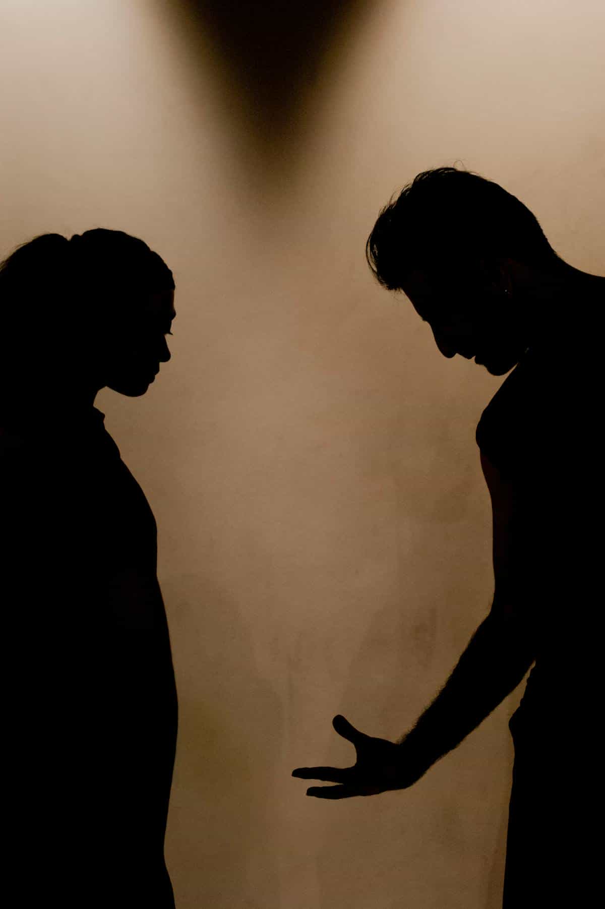 Silhouette argument conveying relationship tension in broken mirror dream interpretation Silhouette of two people in a tense confrontation suggesting relationship strain behind broken mirror dreams