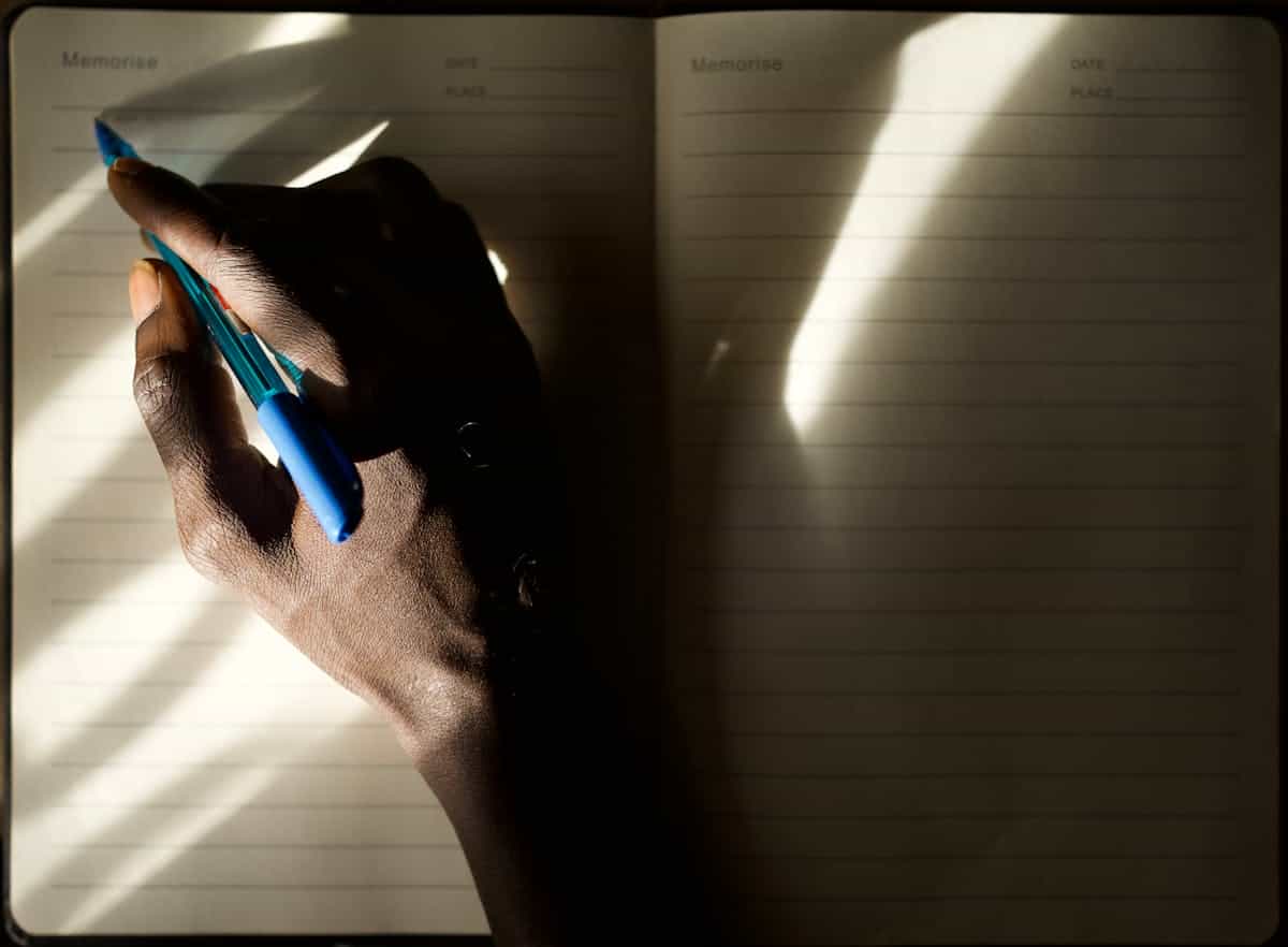 A hand writing in a journal illuminated by soft natural morning light representing the practice of dream journaling and reflection after meaningful dreams