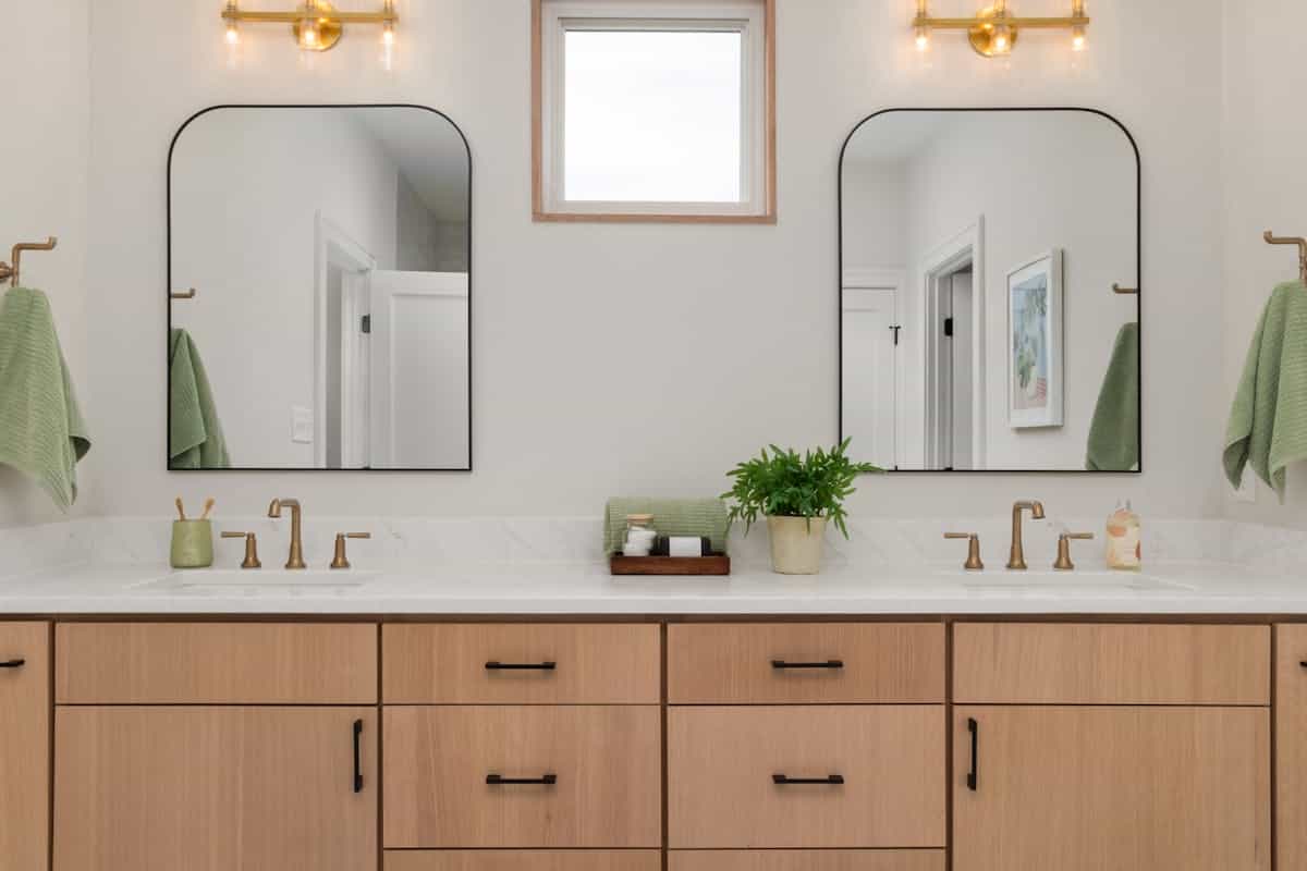 Soft daylight on empty bathroom mirror above washbasin with neutral decor