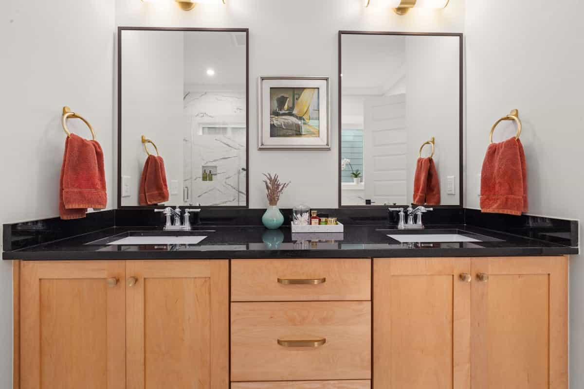 Rectangular black-framed mirrors over a black countertop illustrating black square and long mirror decor Modern vanity with black countertop and rectangular framed mirrors, illustrating black square and long mirrors