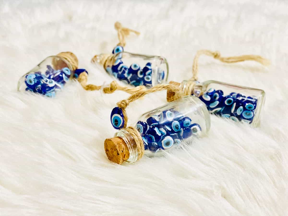 Decorative glass bottles adorned with blue evil eye motifs displayed on soft plaid fabric