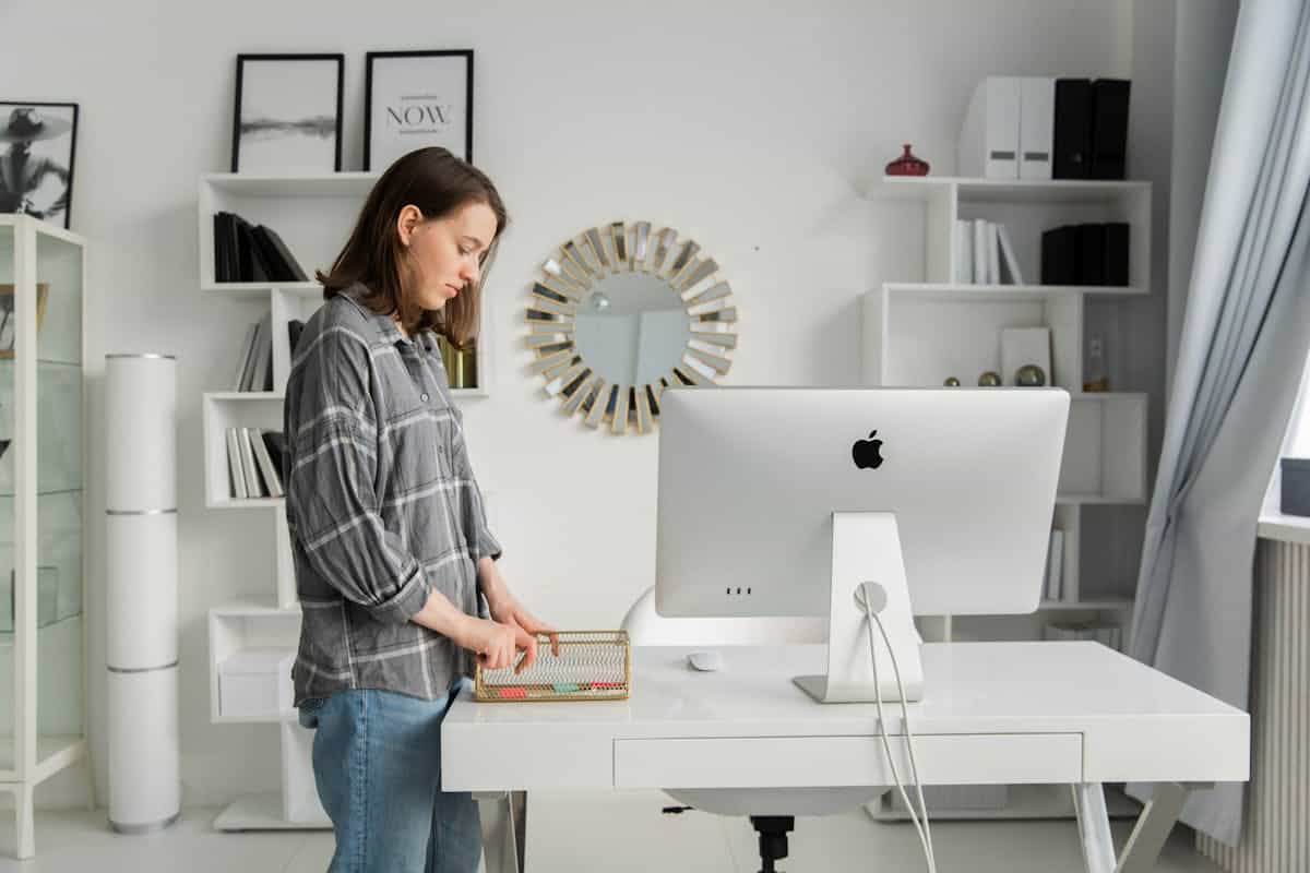 Organizing a home office desk illustrating decluttering and support in a feng shui home office Person organizing a tidy home office desk with shelves, illustrating decluttering in a feng shui home office