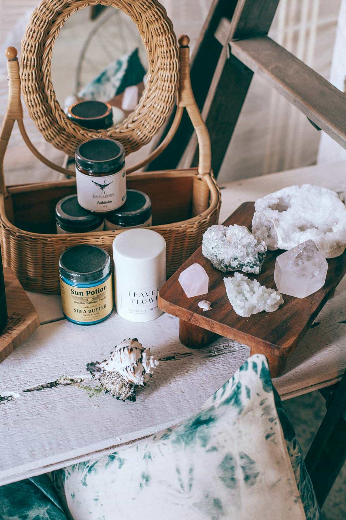 Crystals seashells and jars reflected in mirror for spiritual practice still life Crystals and beauty jars in wicker basket reflected in mirror beside seashells suggesting spiritual cleansing and mirror altar practice