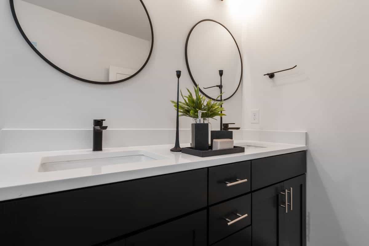 Black and white vanity illustrating why black-framed mirror decor works through contrast Sleek black and white bathroom vanity with framed mirrors, illustrating why black mirror decor works
