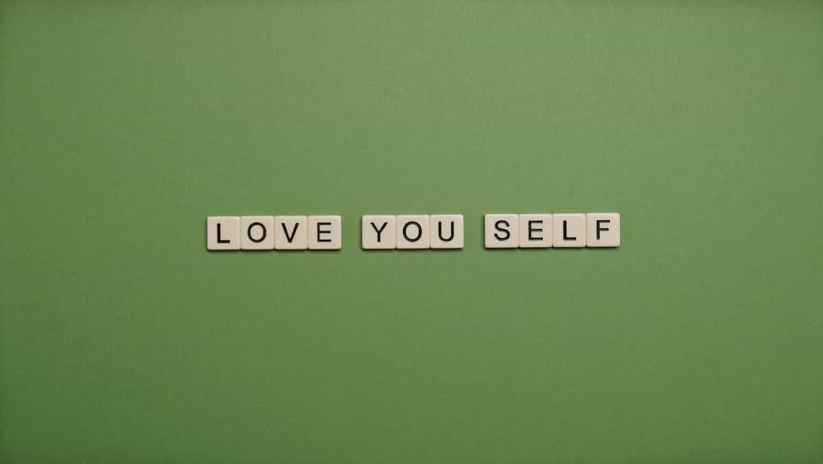 Bright letter tiles spelling out Love You Self arranged on a vivid green background representing self-love and personal affirmation