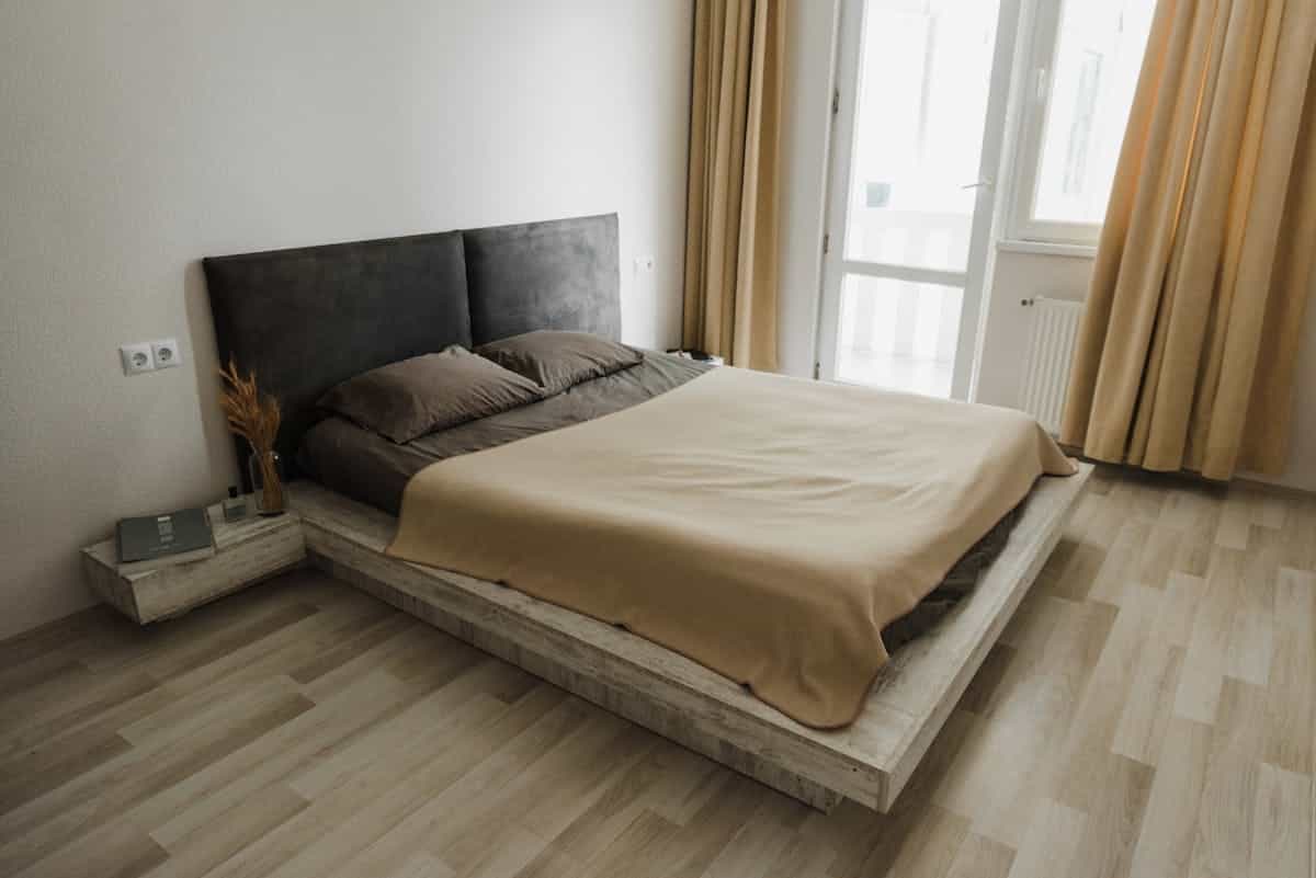 Clean, uncluttered minimalist bedroom in neutral tones with clear floor space, illustrating feng shui energy flow