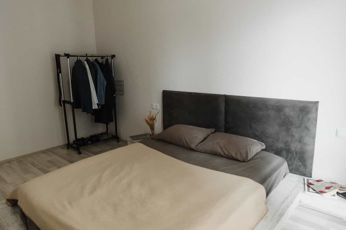 Bedroom in warm beige earth tones illustrating grounding feng shui bedroom colors Minimalist bedroom with beige bedding and a soft grey headboard, illustrating grounding feng shui earth tones