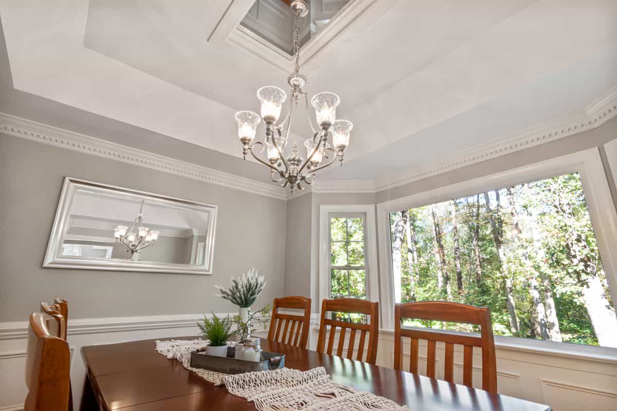 Dining room with a chandelier and wooden furniture where a mirror can double the light