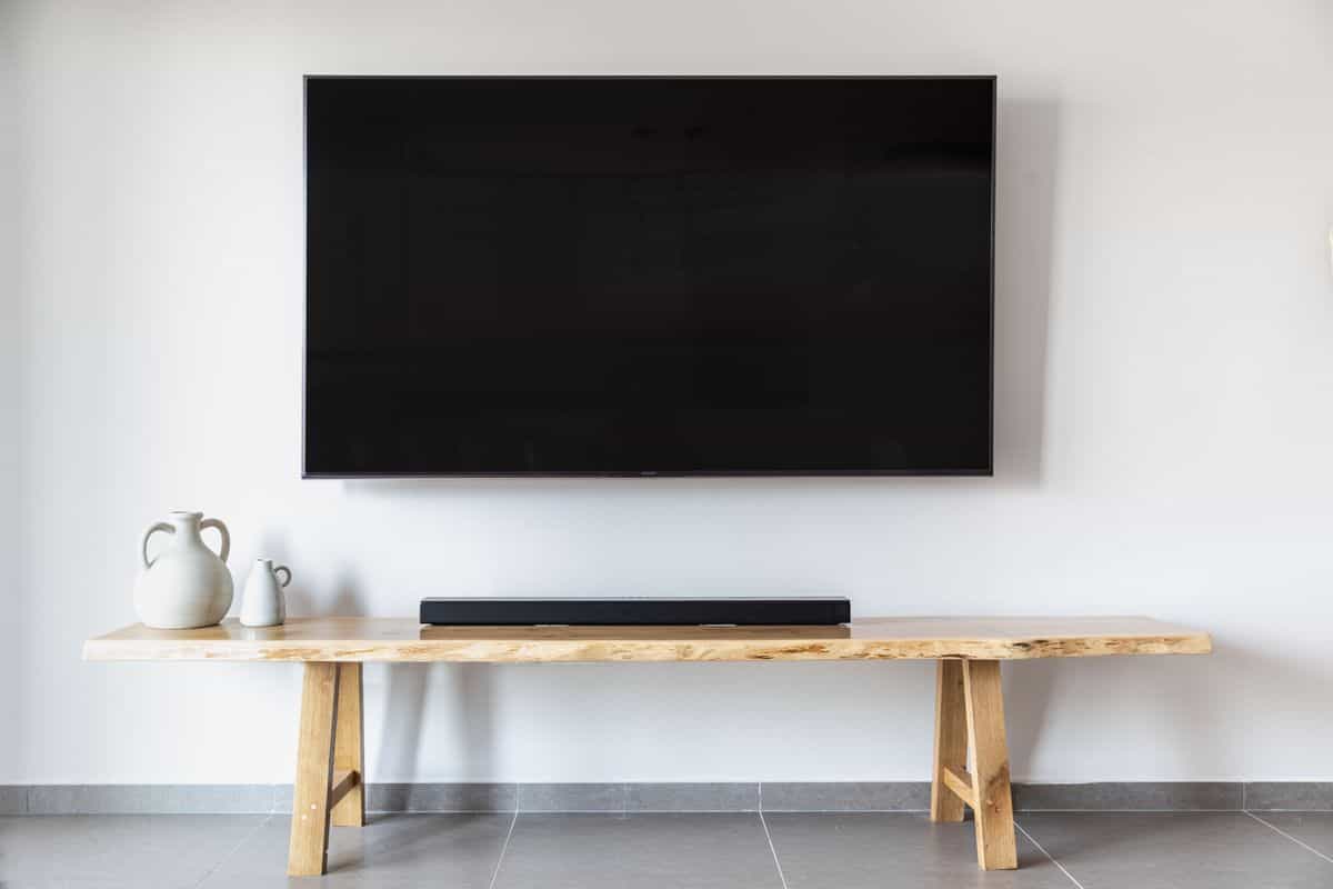 Minimalist living room with a wall-mounted TV above a wooden console, illustrating feng shui TV placement