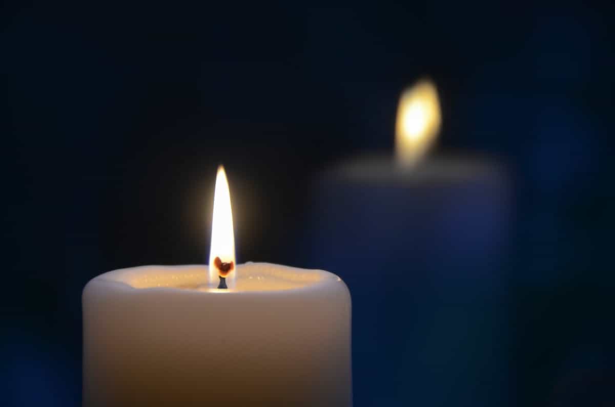 Close-up of a burning candle with a soft warm glow against a tranquil dark background, representing the candlelight cleansing and activation rituals used to consecrate a black mirror for spiritual work