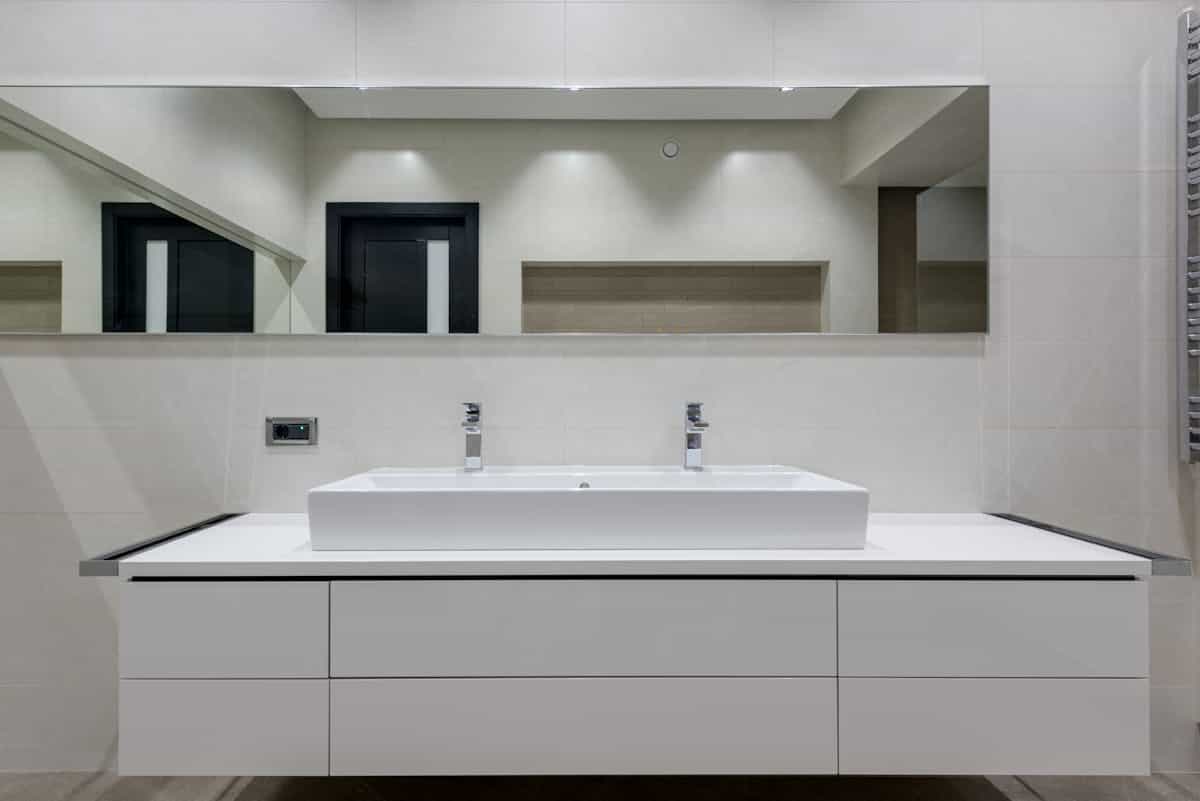 Bright bathroom interior with mirror wall and glass shower partition