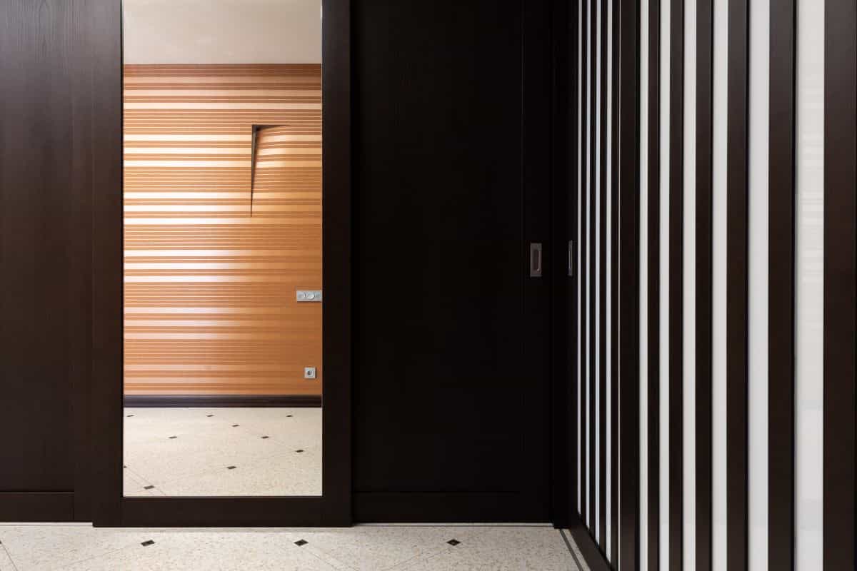 Side-wall hallway mirror reflecting across the corridor to widen a narrow space Hallway with a reflective mirror on a dark side wall, showing why a side-wall hallway mirror works