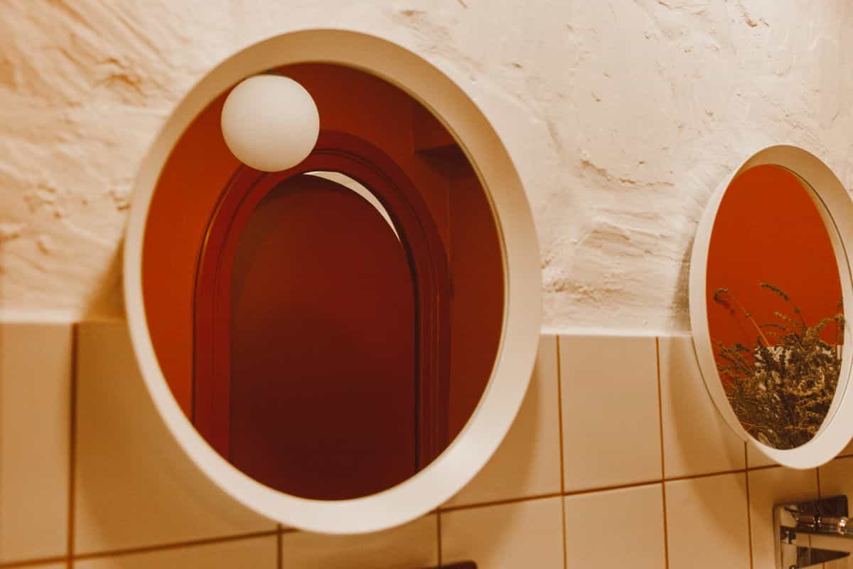 Multiple round mirrors on a textured wall illustrating grouped round mirror decor Elegant interior with multiple round mirrors and warm lighting on a textured wall, illustrating grouped round mirror decor