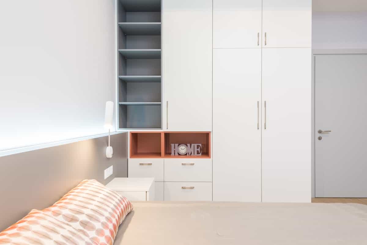 White wardrobe and storage placed against the wall beside a bed, illustrating feng shui bedroom furniture placement