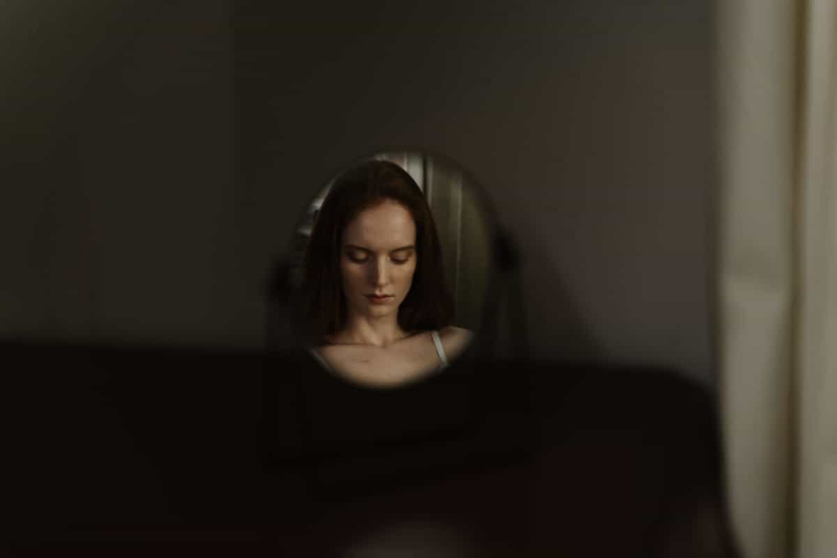 Contemplative round mirror reflection composition for mirror dream symbolism Woman reflected in a round mirror with soft focus creating a contemplative composition about self-perception in dreams
