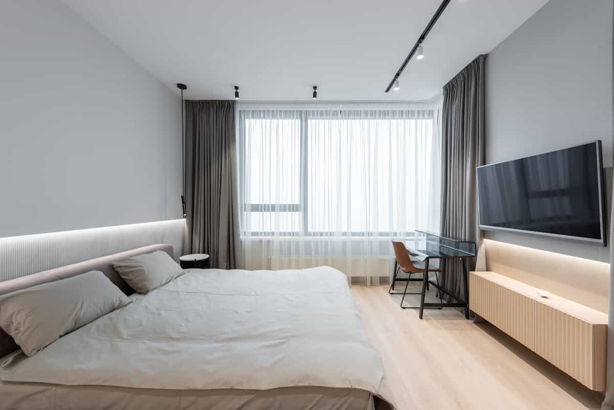 Bedroom with a TV facing the bed illustrating electronics that work against feng shui rest Modern bedroom with a flat-screen TV mounted opposite the bed, illustrating electronics to avoid in feng shui