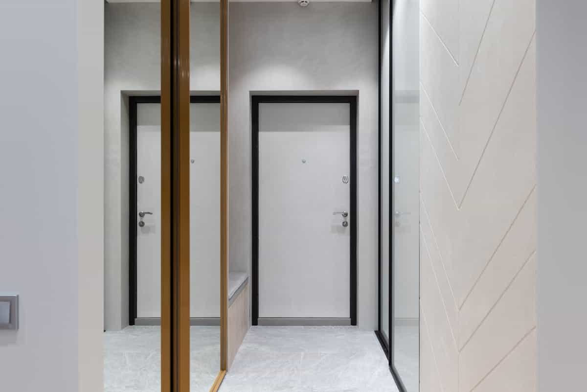 Built-in floor-to-ceiling wardrobes with mirrored panels along a hallway wall as a built-in mirror wardrobe design