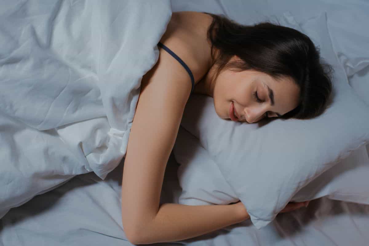 Person sleeping peacefully in a calm bedroom, illustrating the feng shui sleeping direction question.