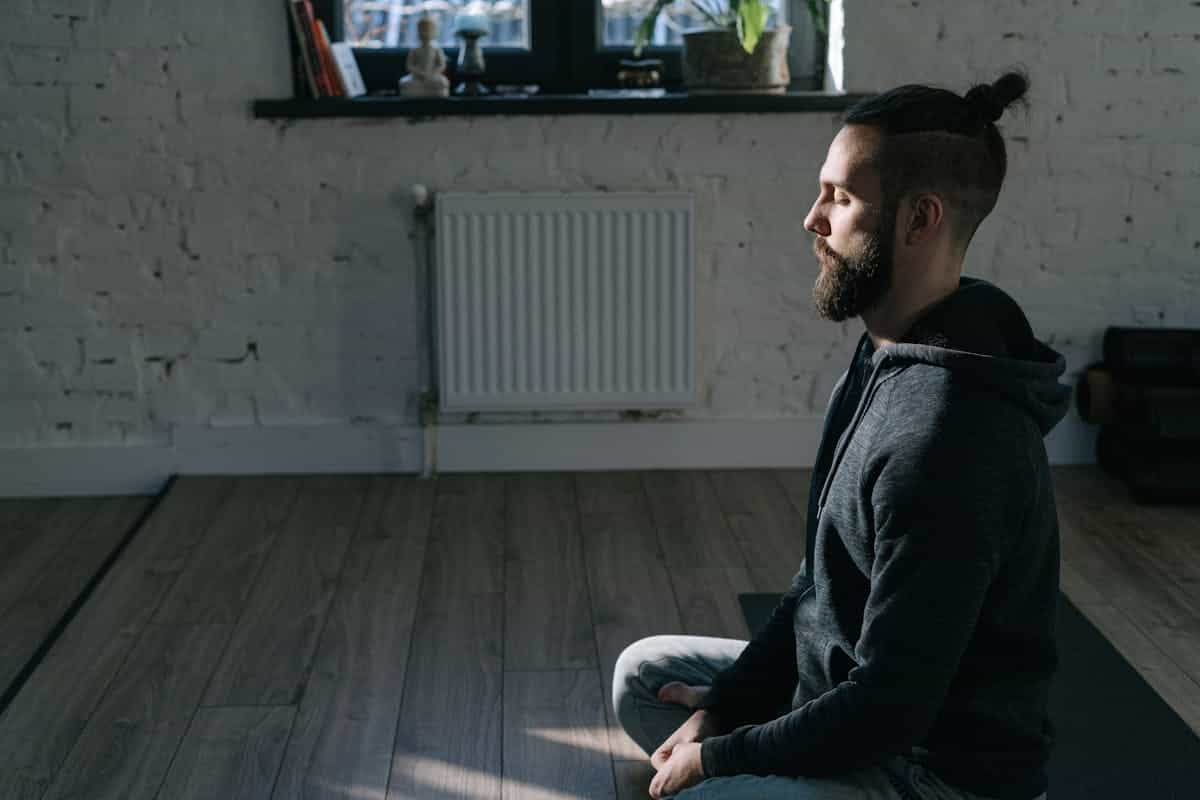 A man in a relaxed meditative posture sitting calmly in a peaceful indoor setting, embodying inner stillness and self-acceptance