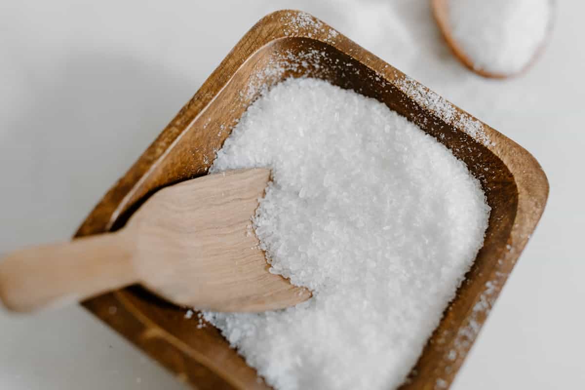Sea salt crystals piled in a wooden bowl beside soft natural kitchen light