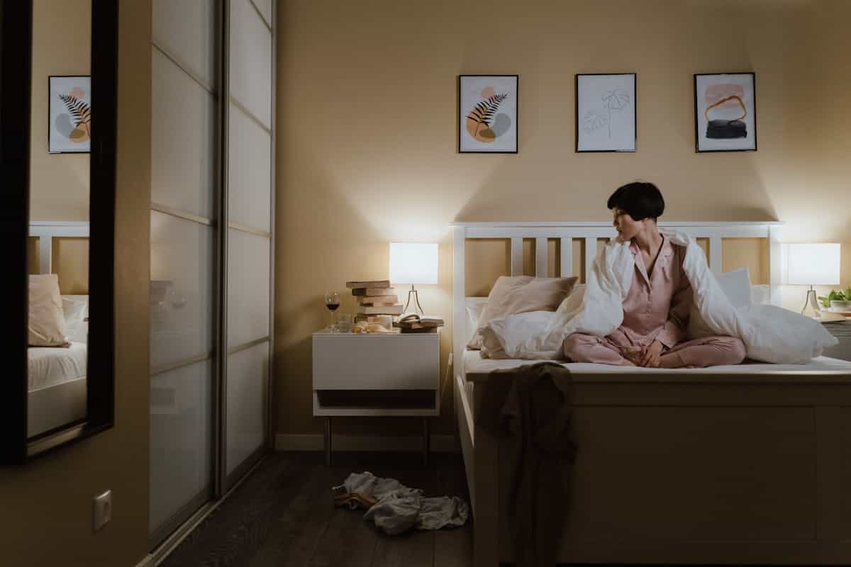 Woman resting in a warmly lit bedroom at night, relating to whether a mirror facing the bed disrupts sleep