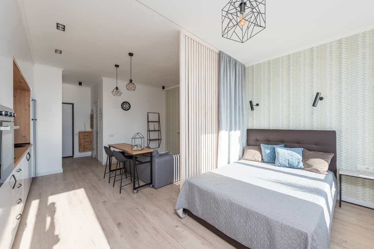 All-in-one studio apartment illustrating the central feng shui challenge of a small space Light studio apartment with a bed and sofa against a white kitchen, illustrating the feng shui studio challenge