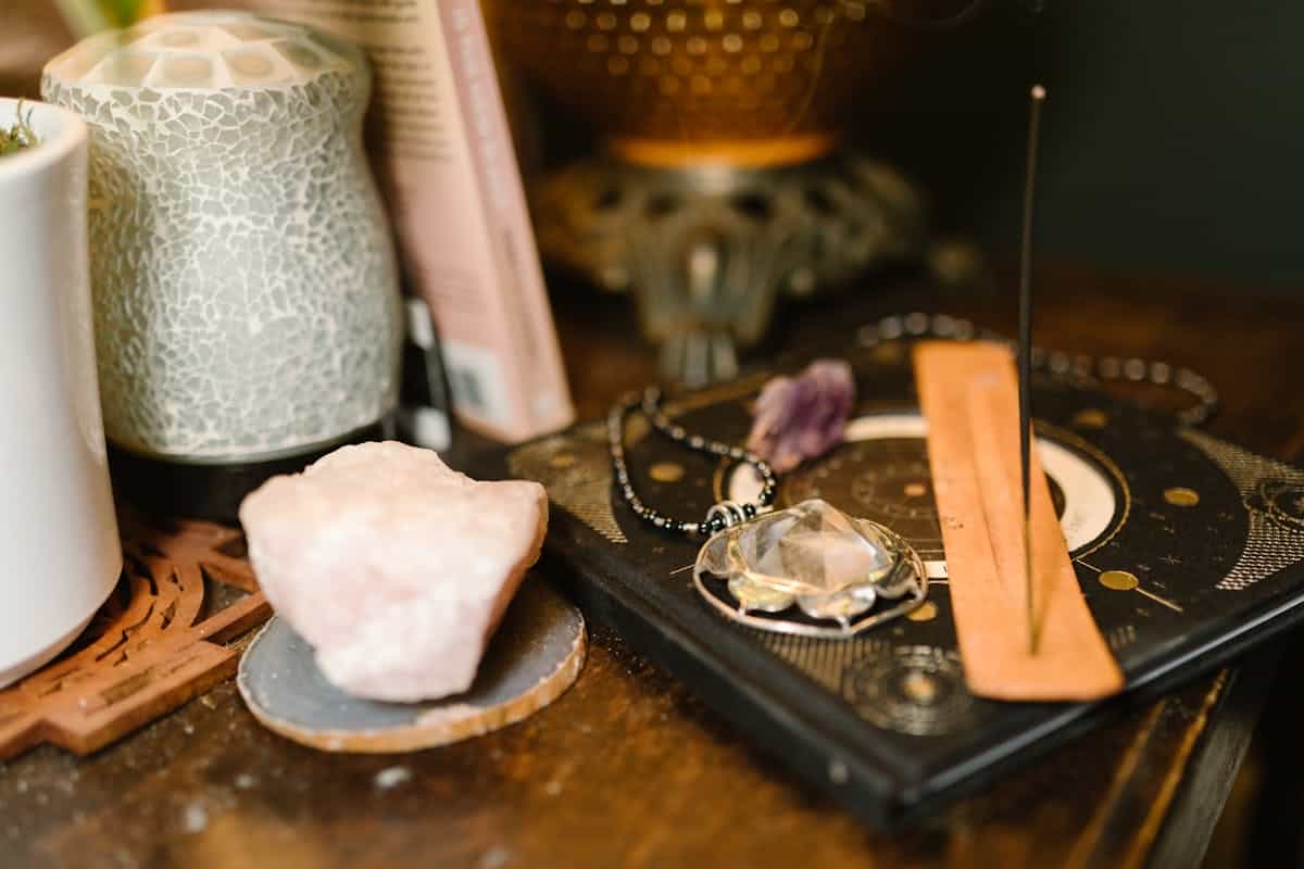 Warm-toned composition featuring incense, rose quartz, and mystical spiritual items on a wooden surface, representing Feng Shui cleansing practices and mirror energy management