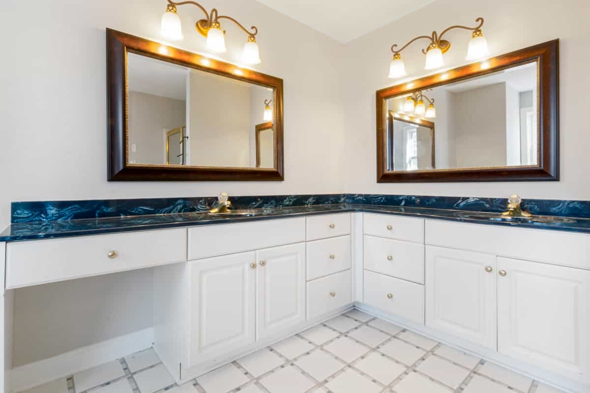 Bathroom vanity with mirrors illustrating how high to hang a vanity mirror Spacious bathroom with dual mirrors and elegant lighting, illustrating vanity mirror placement height