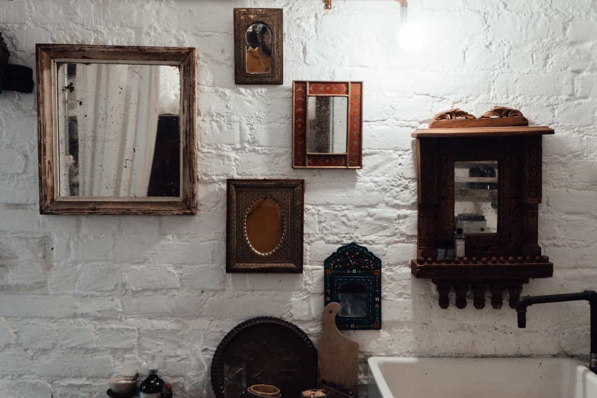 Aged antiqued mirrors illustrating antiqued and smoked mirror wall panels for a living room Aged antique mirrors in decorative frames on a textured wall, illustrating antiqued mirror wall panels