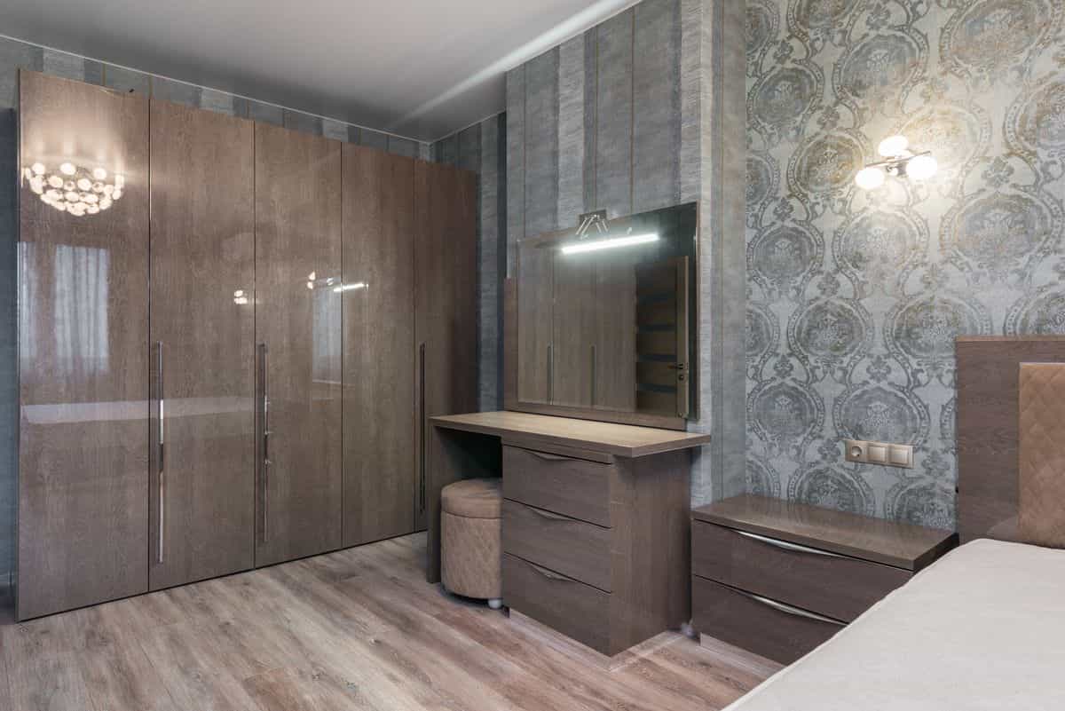 Chest of drawers with an attached mirror showing a matched dresser and mirror set Glossy chest of drawers with an attached mirror in a bedroom as a dresser-and-mirror set