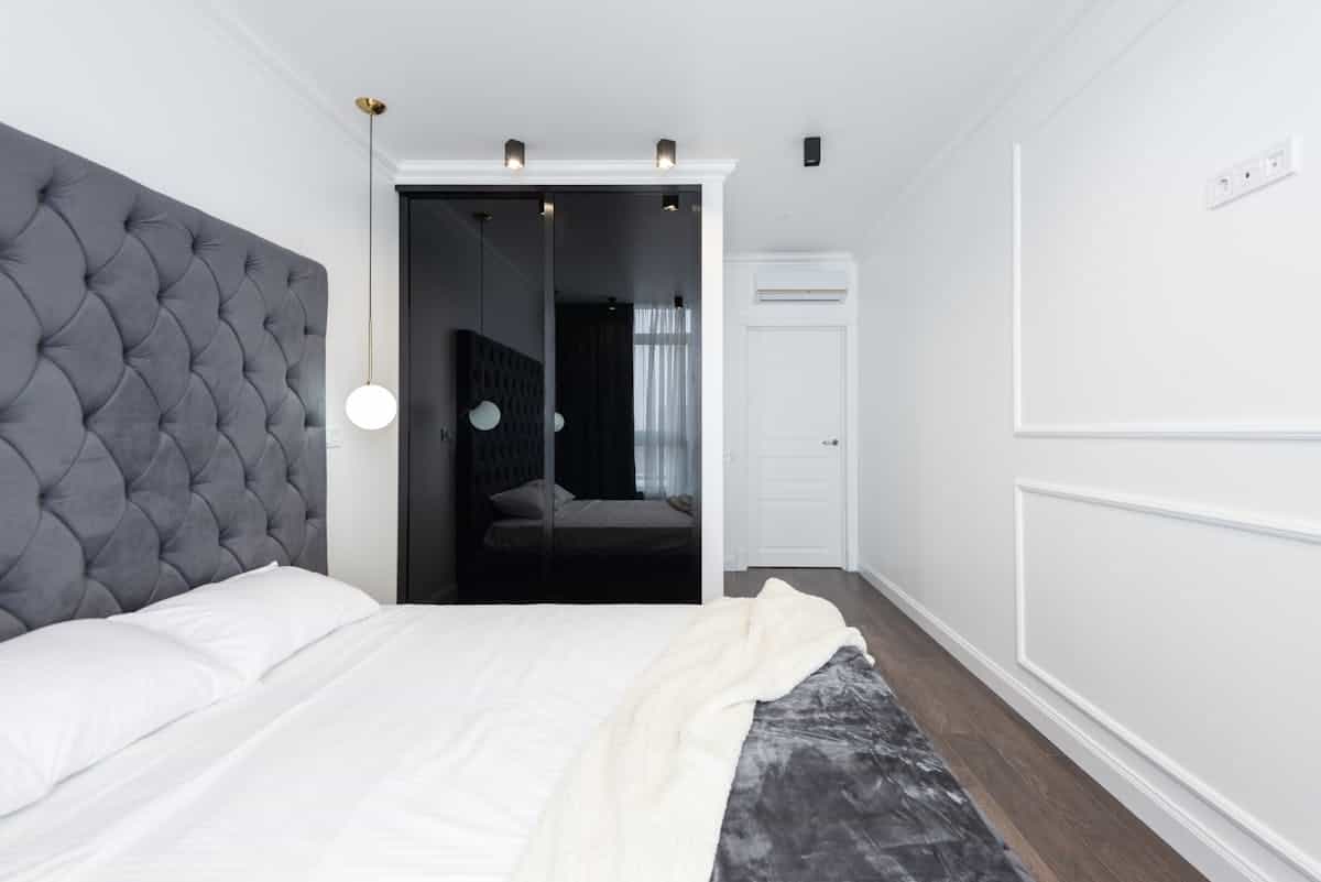 Clean contemporary bedroom with a grey headboard and uncluttered white walls, illustrating what to avoid in feng shui