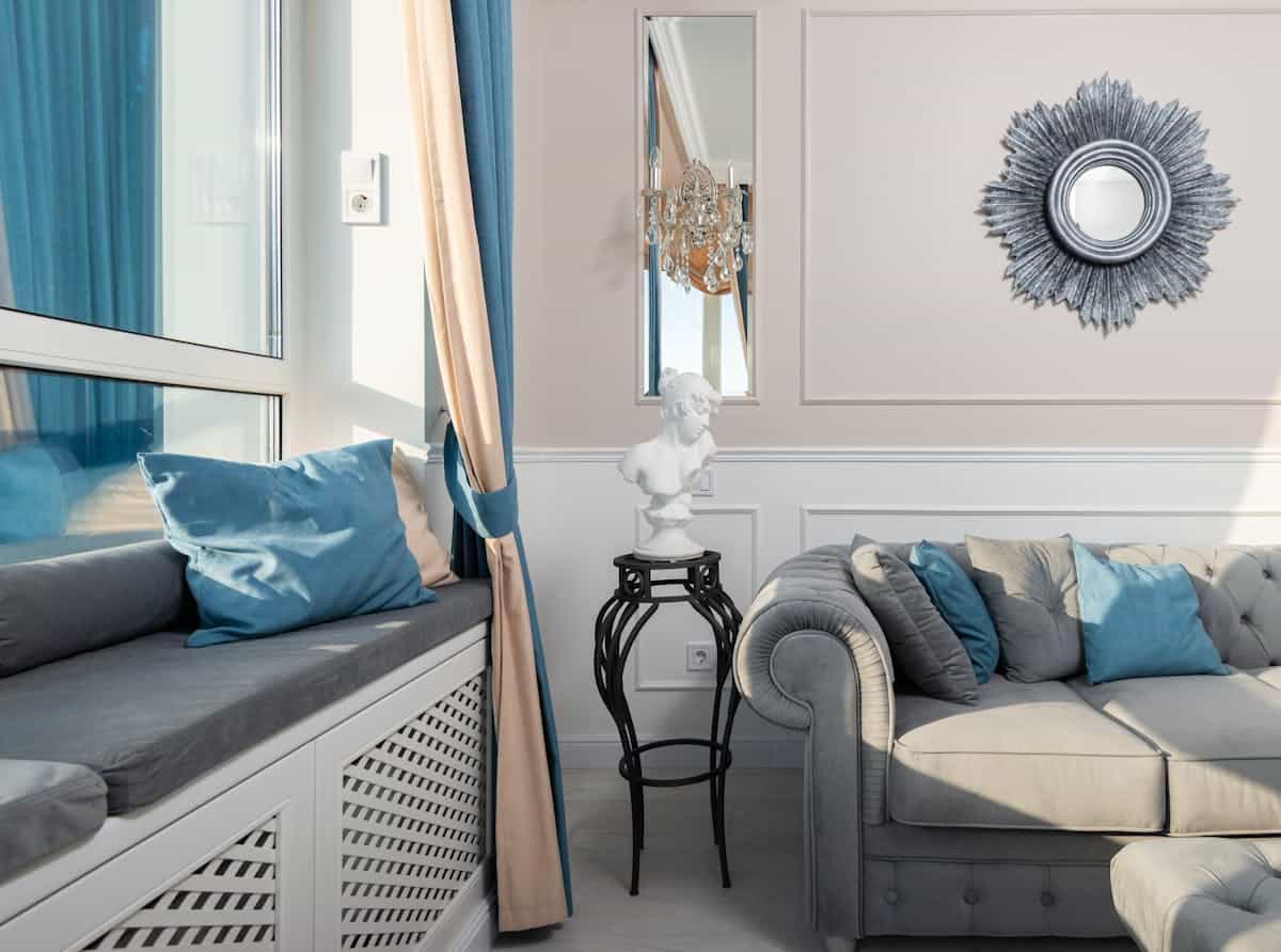 Mirror hung above a sofa illustrating the correct height and spacing over a couch Sofa with cushions beneath a wall mirror on a sunny day, illustrating mirror over sofa height and placement