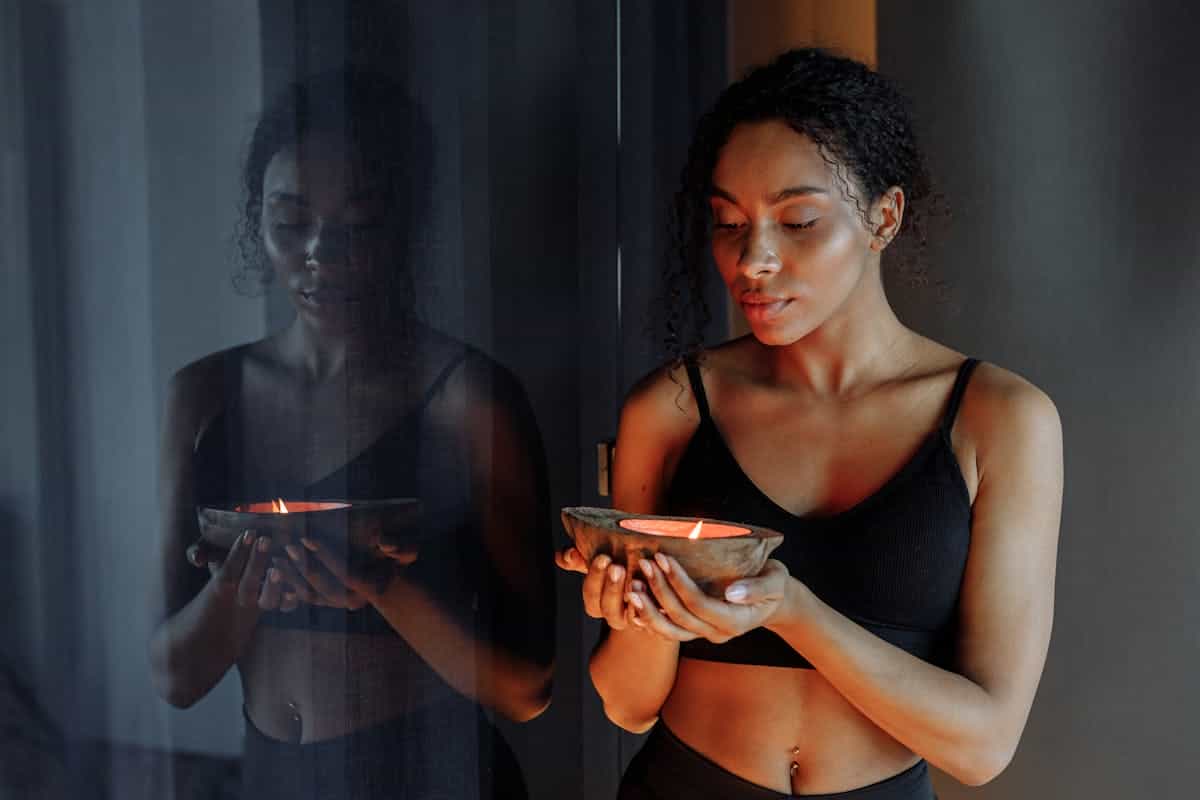 Person in a calm seated meditation posture near candlelight suggesting grounding before intentional self-talk