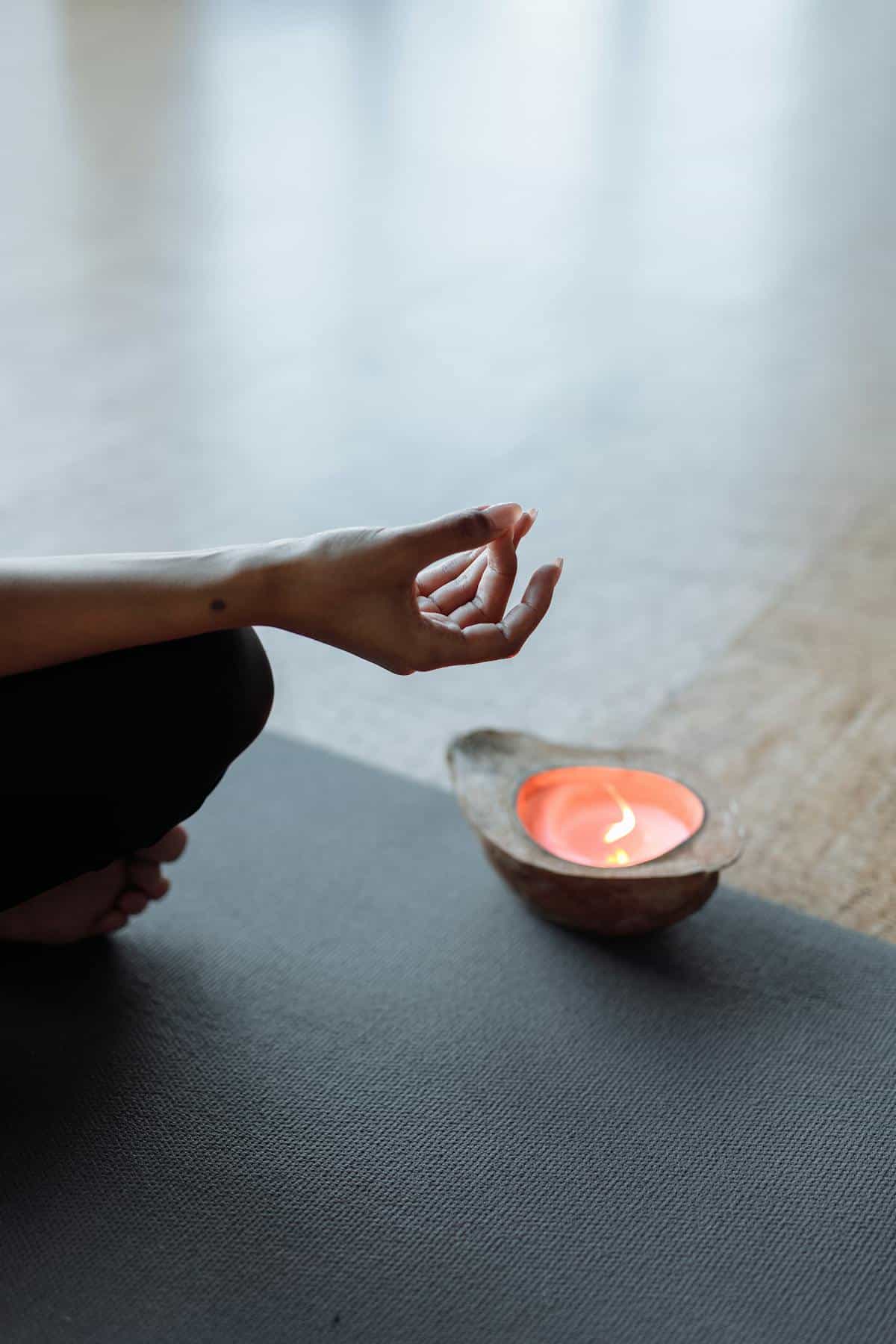 Serene meditation space with hand mudra and candlelight suggesting reflective calm