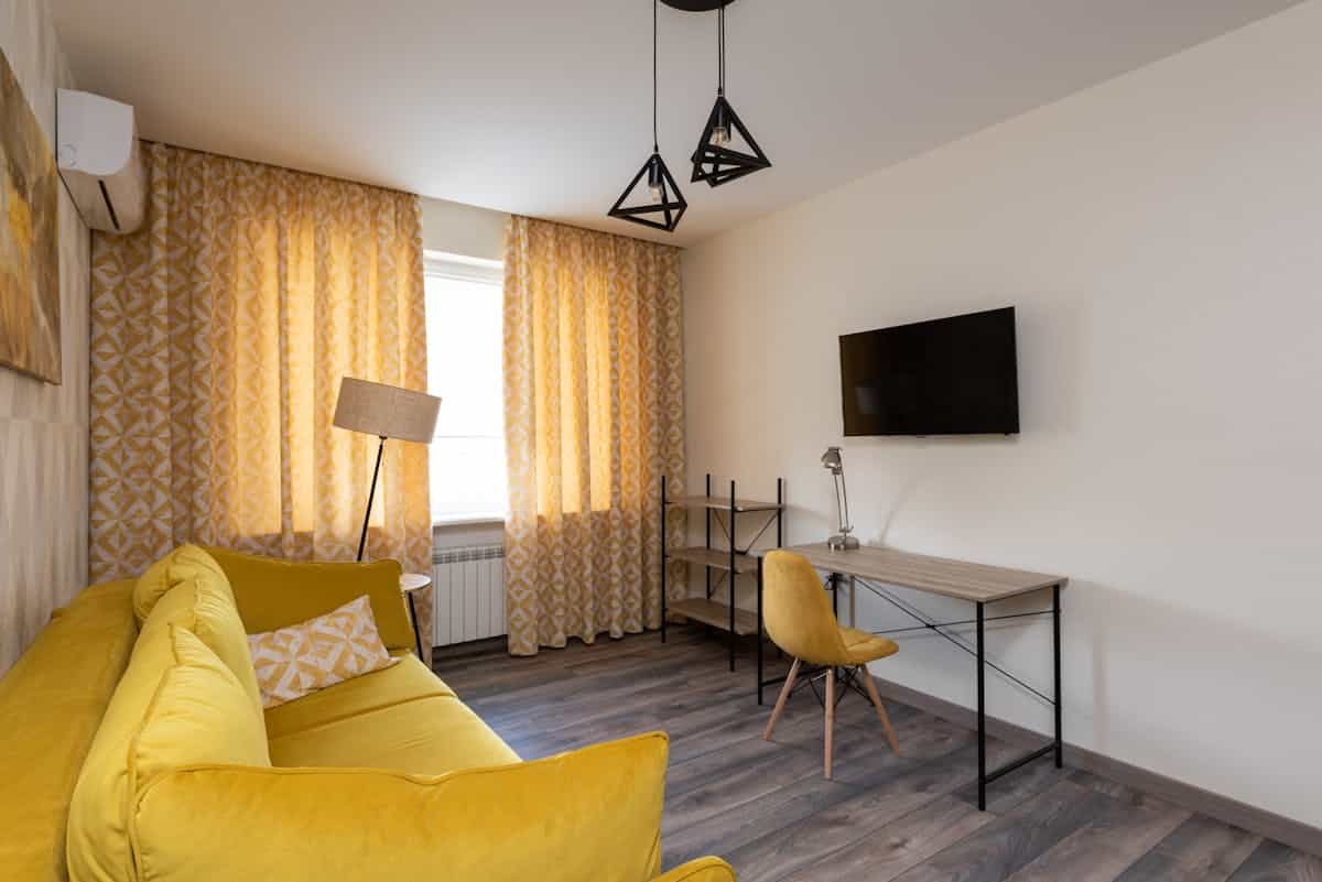 Living room in warm yellow tones illustrating sociable feng shui living room colors Modern living room in warm yellow tones with sofa and cushions, illustrating warm feng shui social colors