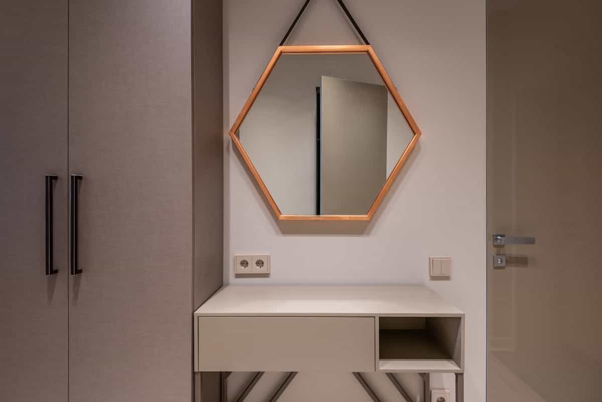 Mirror mounted above a cabinet illustrating the correct dresser mirror size and height Mirror hanging on the wall above a low cabinet showing how high to hang a dresser mirror