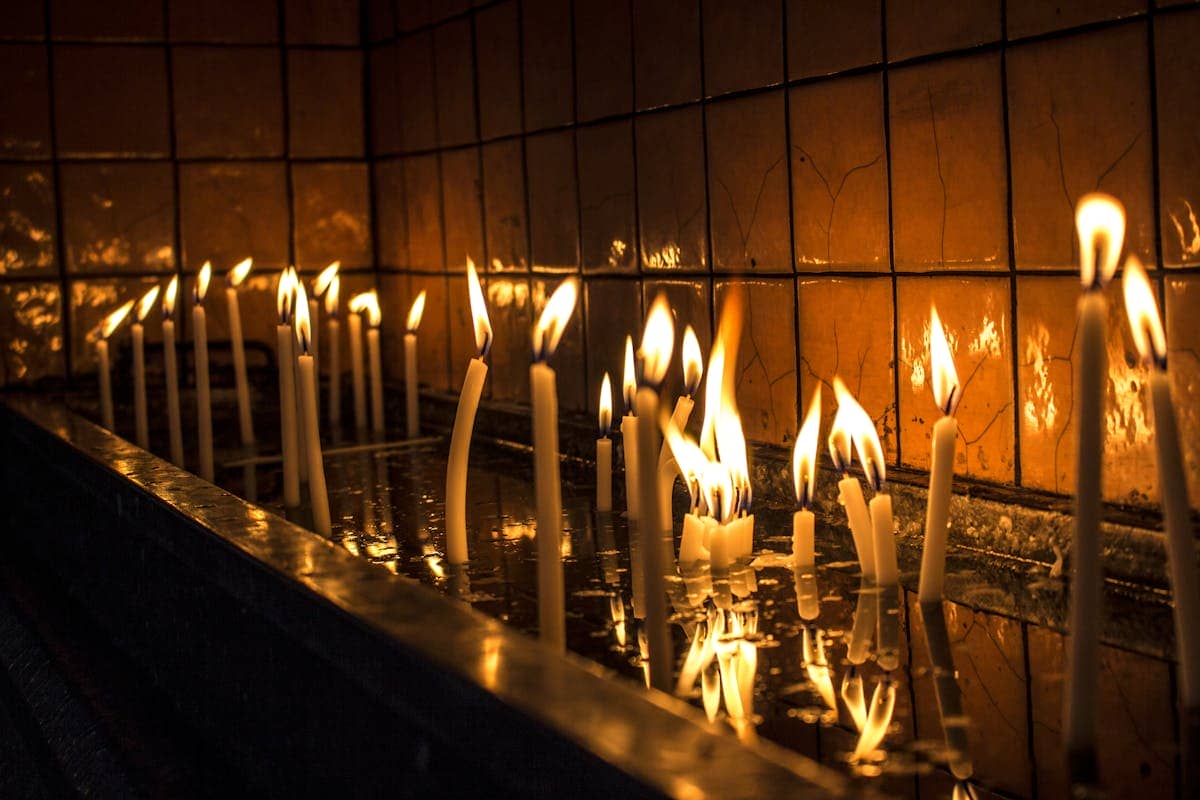 Lit candles reflecting on a dark polished surface in a tranquil setting evoking the atmosphere of a scrying session