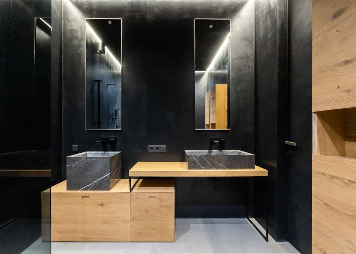 Mirrors against a dark wall illustrating the black mirrored wall contrast rule Modern washroom with mirrors against a dark wall, illustrating the contrast rule for black mirror decor