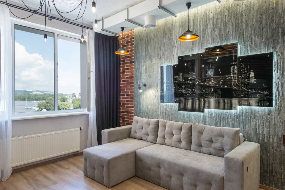 Living room with a large artwork above the sofa illustrating art-led accent wall ideas Living room with large artwork above a sofa beside a window, illustrating art as a living room accent wall