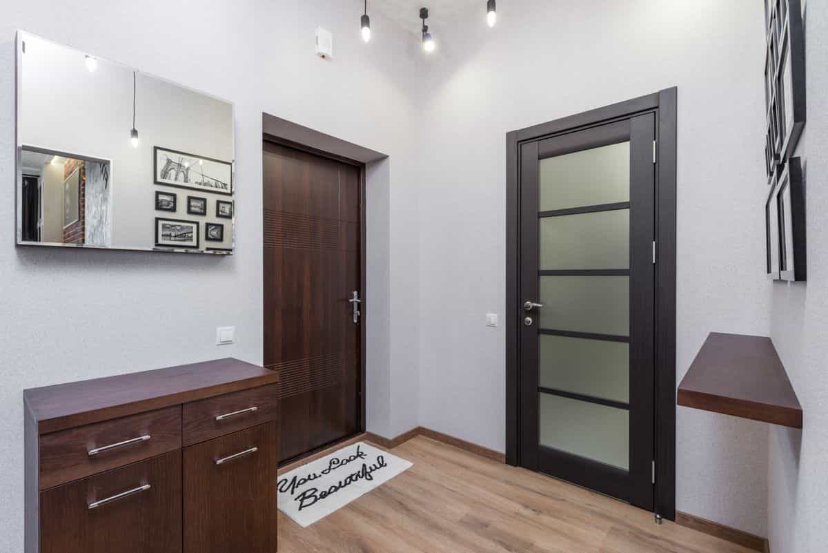 Stylish entryway with dark wood elements, a wood-framed mirror, and framed art, illustrating wood types for mirror frames