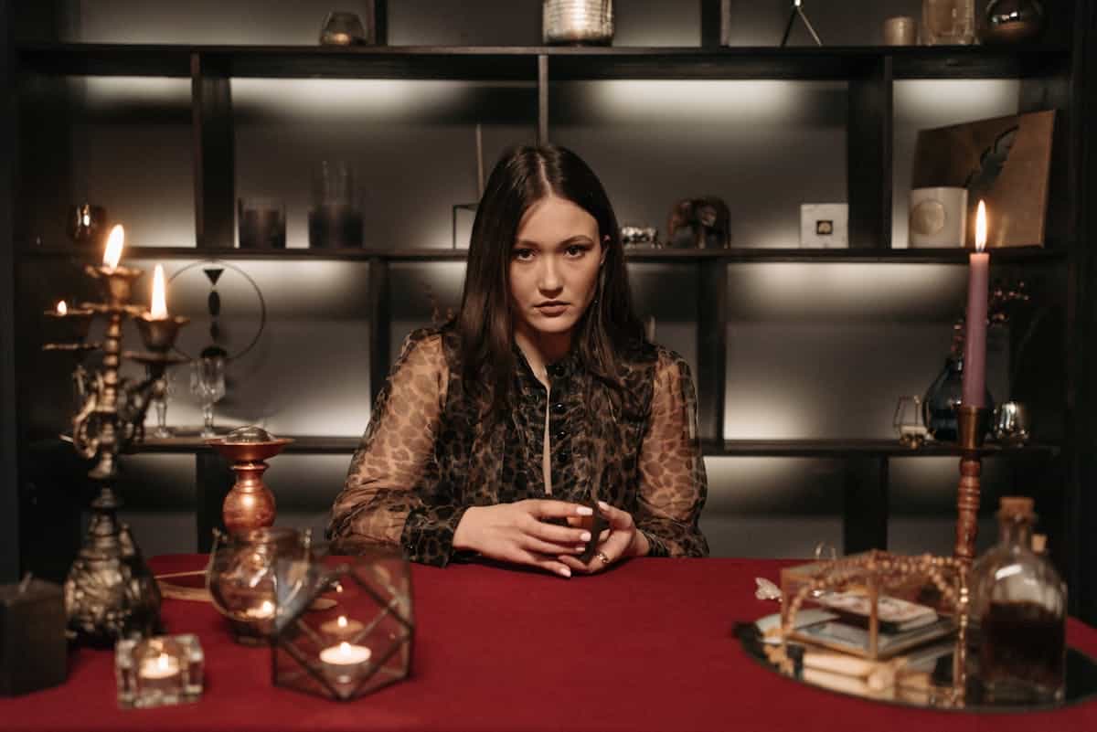Mysterious woman in a dimly lit room engaged in fortune telling with candles and tarot cards creating a spiritual atmosphere