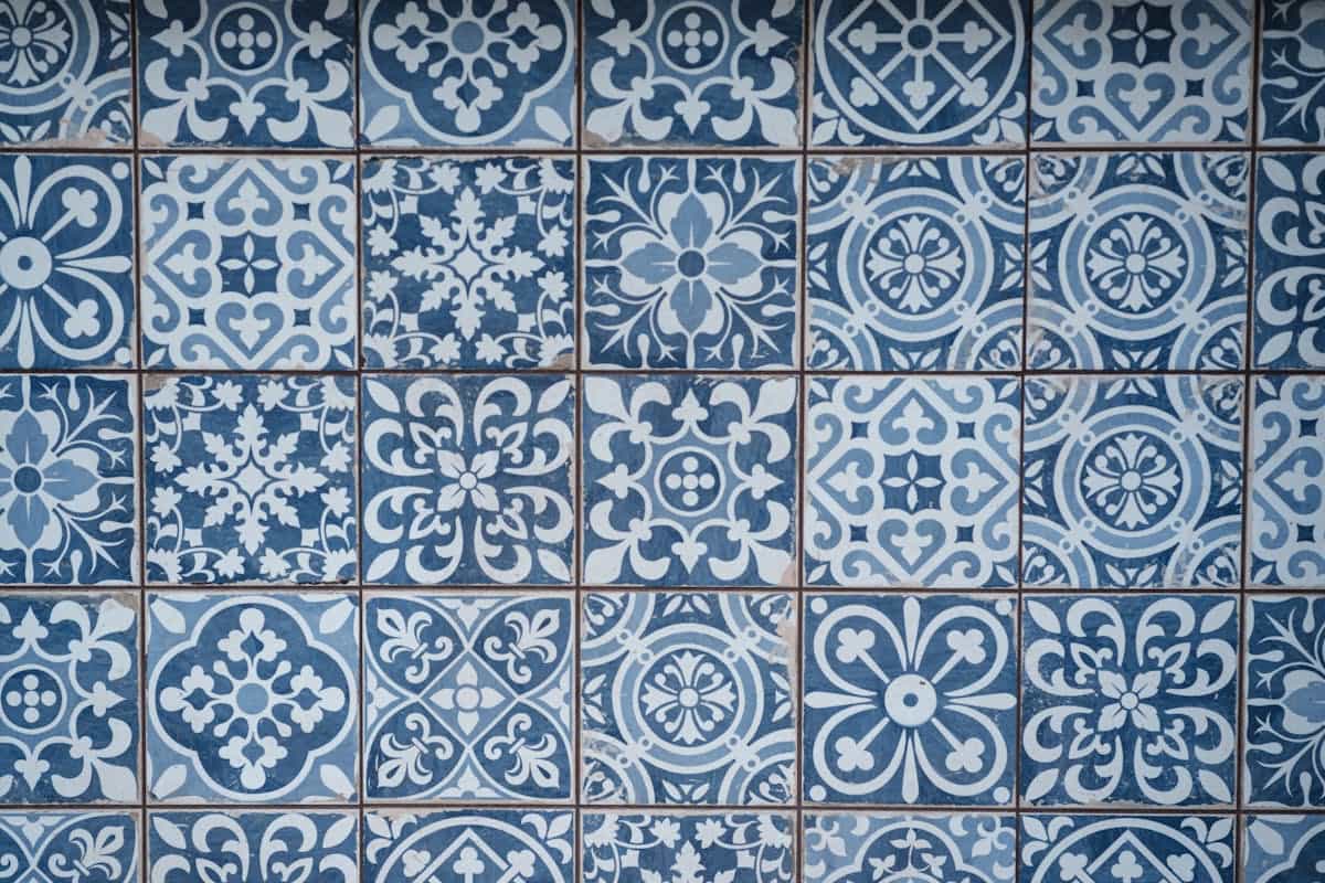 Weathered wall of blue and white Mediterranean ceramic tiles with geometric patterns